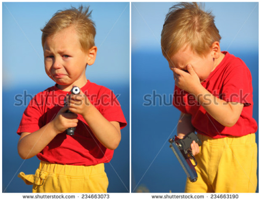 A young boy crying and holding a handgun 