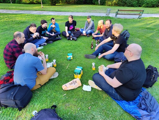 Group of KDE Plasma developers sitting in a circle on the grass in a park 